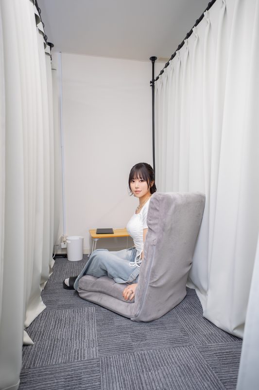 個室ブースの中で座椅子に座ってくつろぐセラピスト
